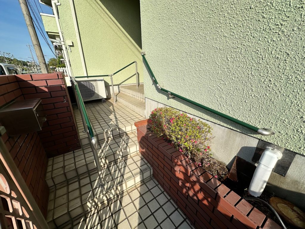 建物の外側にある階段と手すり、周囲に植え込みがある景色